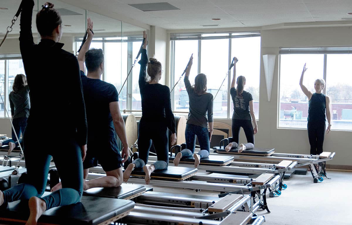 Pilates Process Toronto Instructor and student group on pilates reformers captioned 'Pilates Reformer Classes'