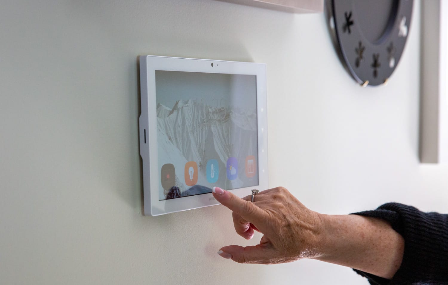 Smart home touchscreen control panel mounted on a wall, providing intuitive access to lighting, climate, and security settings.